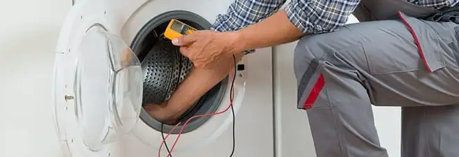 Dryer repair technician inspecting and repairing a clothes dryer in Henderson, NV