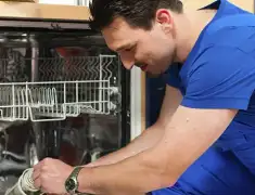 Dishwasher repair technician inspecting and servicing an open dishwasher in Henderson, NV