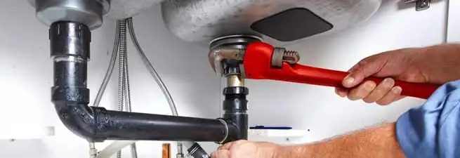 Garbage disposal repair technician tightening the sink drain and disposal connection in Henderson, NV