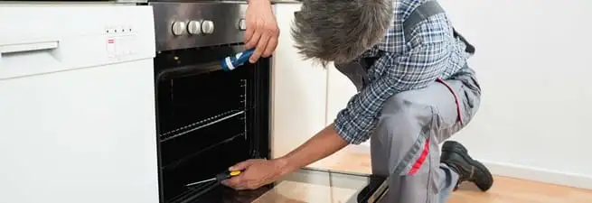 Oven repair technician inspecting and servicing an electric oven in Henderson, NV