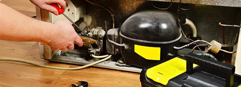 Refrigerator repair technician fixing the compressor and wiring in Henderson, NV