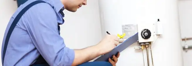 Water heater repair technician inspecting the unit and recording service notes in Henderson, NV
